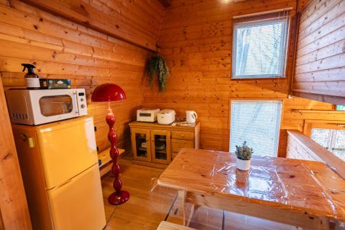 a kitchen with a refrigerator and a table in a cabin at -Secret Bloom- 可愛いがギュッと詰まったパン屋さんとサファリパークに近い黄色いコテージ in Nasu-yumoto