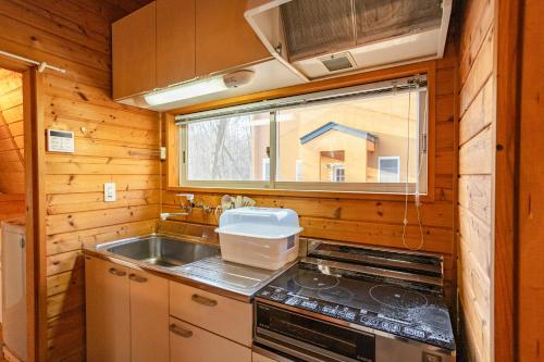 a kitchen with a stove and a sink and a window at -Secret Bloom- 可愛いがギュッと詰まったパン屋さんとサファリパークに近い黄色いコテージ in Nasu-yumoto