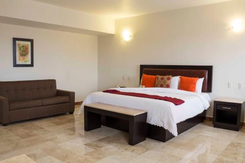 a bedroom with a large bed and a couch at Imperio de Angeles Executive León Poliforum in León