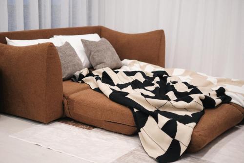 a brown couch with a black and white blanket on it at 'Amber' 1 bedroom apt in Burwood with free parking in Sydney