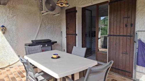 a dining room with a white table and chairs at La maison près de la cascade. in Rochecolombe