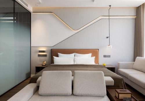 a bedroom with a bed and a couch at Bassac Signature Hotel & Residence in Phnom Penh