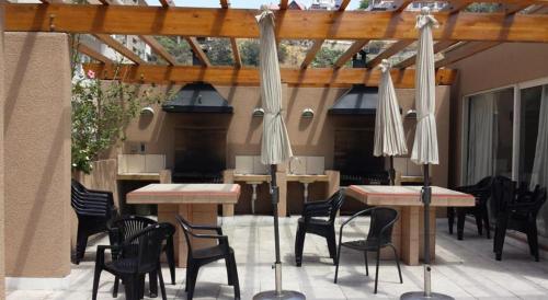 un patio con tavoli, sedie e ombrelloni di Departamento Aquamar 2 a Viña del Mar