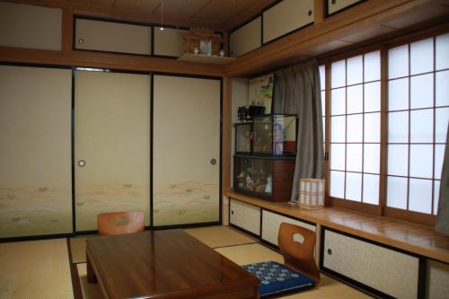 een eetkamer met een tafel, stoelen en ramen bij Umeya Annex in Fujikawaguchiko