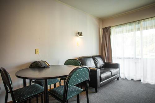 a living room with a couch and a table and chairs at Bennetts Thermal Motor Inn in Tauranga