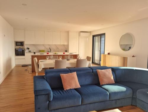 a living room with a blue couch and a kitchen at Sisters Apartamento -200m2 centre ville in Ponte da Barca