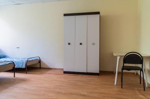 a room with a white cabinet and a bed and a table at Sicheslav Hostel in Dnipro