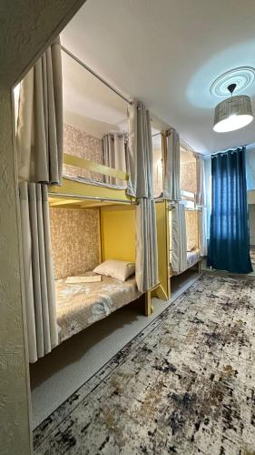 a room with two bunk beds with blue curtains at Premium Hostel Atyrau in Atyrau