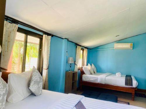 una stanza con due letti e una parete blu di Busaba Villa Sea Views a Tha Sala