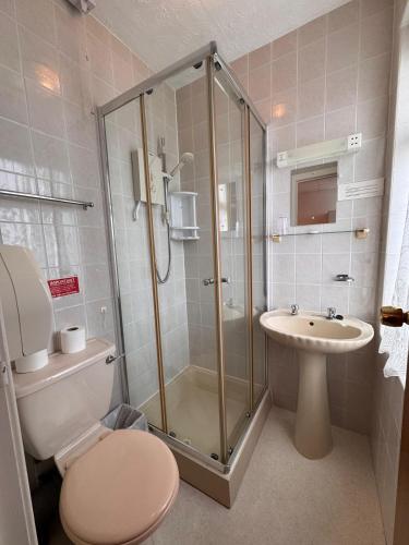 a bathroom with a shower and a toilet and a sink at Pleasure Beach Hotel by OYO in Blackpool