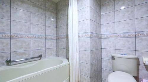 a white bathroom with a tub and a toilet at Red Cabin Inn in Taipei
