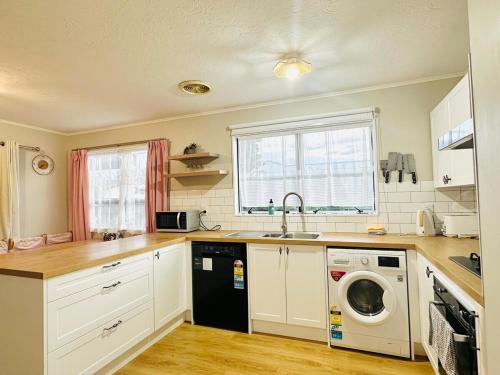 a kitchen with a sink and a washing machine at Waiwhetū 3 bedrooms house Retreat in Lower Hutt