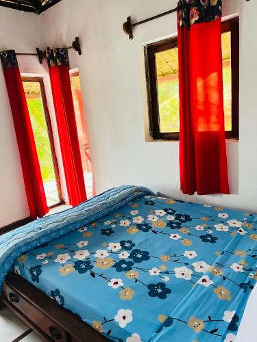 a bedroom with a bed with a blue comforter and windows at Nosy-Borah Holidays in Analabe