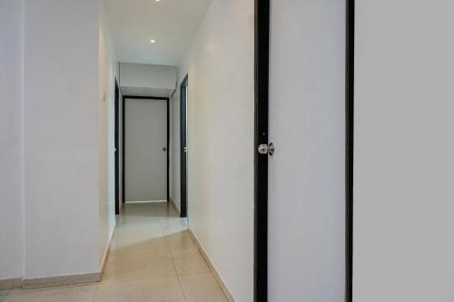 an empty corridor with white walls and a door at Super Hotel O Happy Homely Stay in Pune