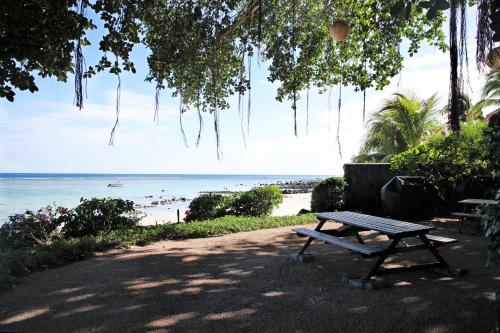 a picnic table sitting next to a beach at Sunset Coast Apartment in Rivière Noire