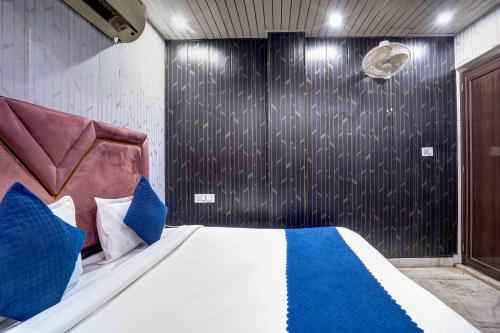 a bedroom with a bed with blue and white pillows at Anvit Residency - By The Arrow in New Delhi