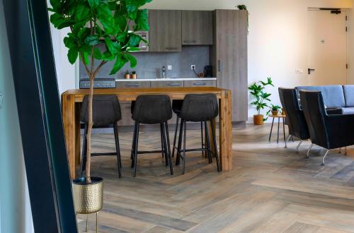 a kitchen with a wooden counter with black bar stools at Xl Newly Built Nature Villa, Wifi in Ledeacker