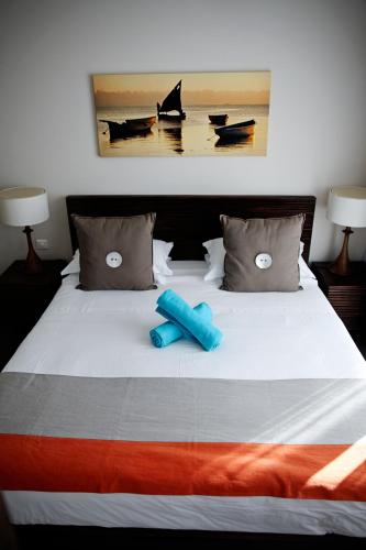 a white bed with two blue pillows on it at Sunset Coast Apartment in Rivière Noire