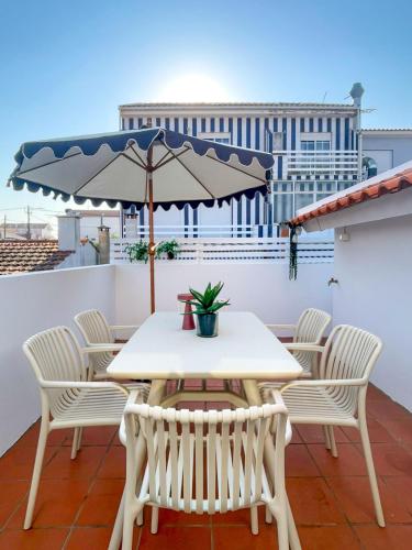 a table and chairs on a balcony with an umbrella at Pijamas House in Gafanha da Encarnação