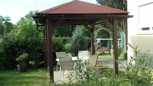 a wooden gazebo with white chairs in a yard at Haus Floresa in Lutzmannsburg