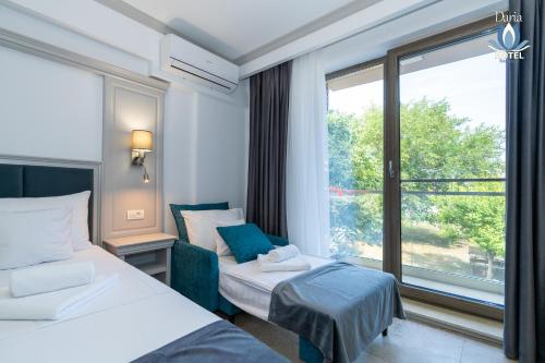 a hotel room with two beds and a large window at Daria Boutique Hotel in Eforie Sud