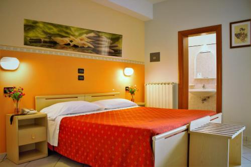 una camera da letto con un grande letto con una coperta rossa di Hotel Monica a Chianciano Terme