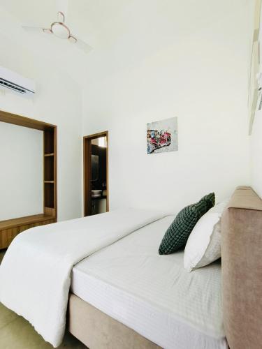 a bedroom with a large white bed with a couch at Ivy House in Khanivde