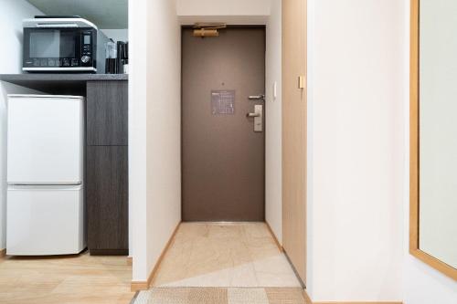 a hallway with a kitchen with a refrigerator and a microwave at Tokyu Stay Yotsuya in Tokyo
