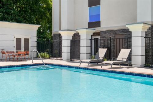 a swimming pool with two chairs and a table at Hampton Inn & Suites Fresno in Fresno