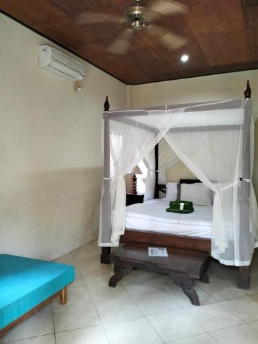 a bedroom with a canopy bed and a blue bench at Villa coral Cafe in Amed