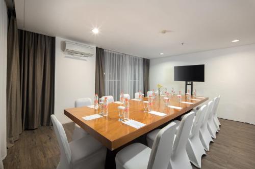 a conference room with a long wooden table and white chairs at The Akmani Legian in Legian