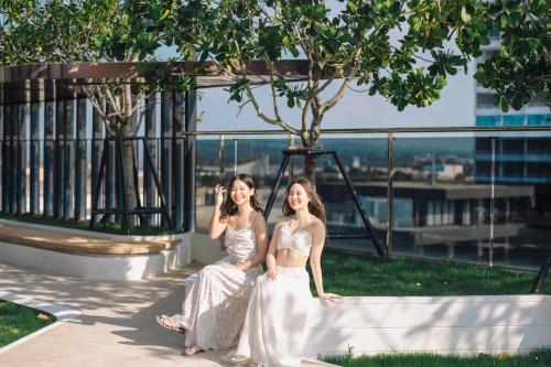 two girls are sitting on a bench on a building at Howard Johnson by Wyndham Pattaya JC in Na Jomtien