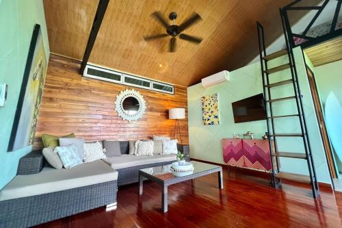 a living room with a couch and a ceiling fan at Casa de Cacao, A Treetop Cottage in Cacao Forest! in Playón
