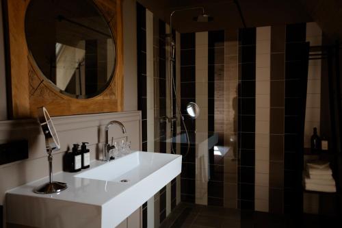 a bathroom with a sink and a shower with a mirror at Hotel Bent in Oisterwijk