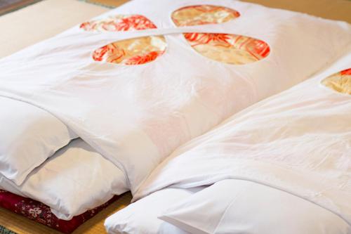 a bed covered in white sheets with pizzas on it at Guesthouse Fujinokura Kawaguchiko Ekimaeten in Fujikawaguchiko
