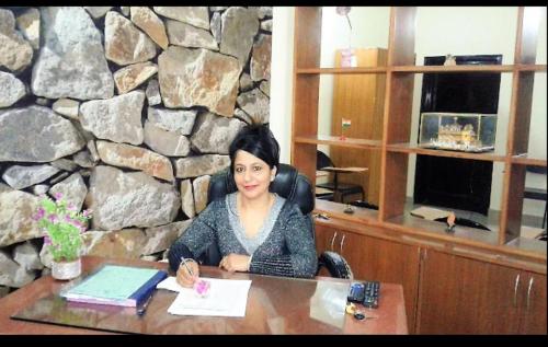 a woman sitting at a desk in an office at New Chandigarh Holiday Home in Chandīgarh