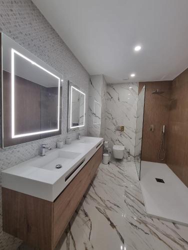 a bathroom with a sink and a mirror and a tub at Sisters Apartamento -200m2 centre ville in Ponte da Barca