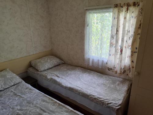 a small room with two beds and a window at Medumi Lake Caravan in Medumi