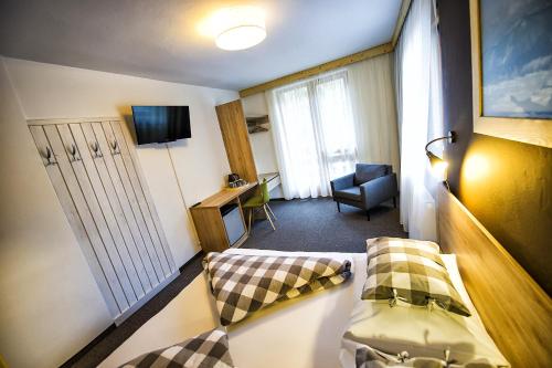 a small room with a bed and a chair at Penzion Flores in Demanovska Dolina
