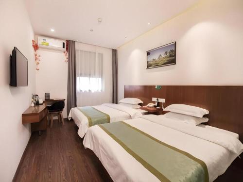 a hotel room with two beds and a desk at Vatica Shanghai Jiading District Anting Metro Station Moyu Road Hotel in Shanghai