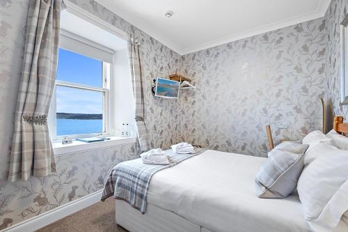 a bedroom with a large bed and a window at No. 1 Charlotte Street in Port Ellen