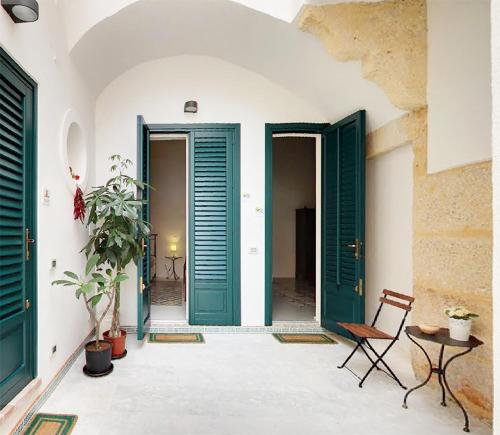 een kamer met groene deuren en een stoel bij Casa Marsalia in Marsala