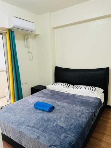 a bedroom with a bed with a blue pillow on it at Vtan Condo in Manila