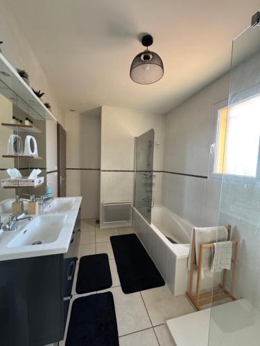 un bagno bianco con vasca e lavandino di Maison avec piscine privée entièrement climatisée a Sauvian