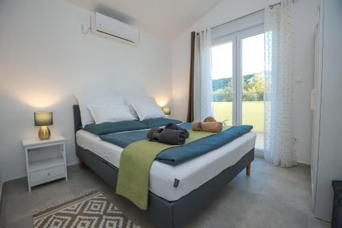 a bedroom with a large bed with blue sheets and a window at Villa Gaby with Heated Pool in Božava