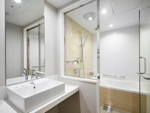 a white bathroom with a sink and a mirror at Daiwa Roynet Hotel Matsuyama in Matsuyama
