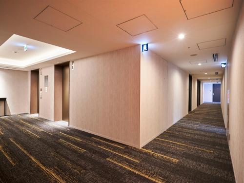 an empty hallway in a building with a wall at Daiwa Roynet Hotel Matsuyama in Matsuyama