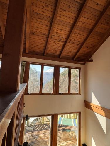 a room with windows and a ceiling with wooden beams at Cabin A MtFuji view, BBQ, lake Saiko 3mins, hammock, wood deck in Narusawa