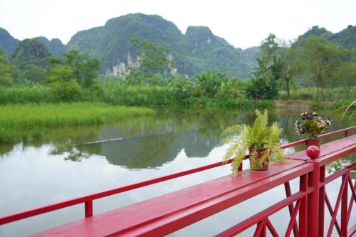 a red bridge with a view of a river at Happy Tam Coc Ecolodge in Ninh Binh
