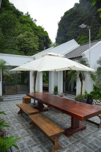 a picnic table with an umbrella on a patio at Happy Tam Coc Ecolodge in Ninh Binh